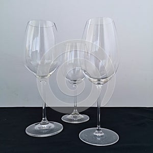 3 empty wine glasses for white wine on black table and white background Close up photo
