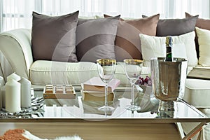 Wine glasses and wine bottle on table with beige sofa with dark brown pillows