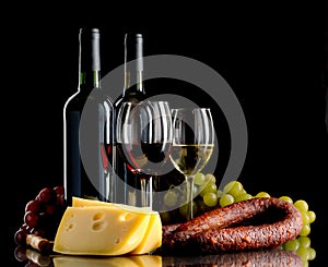 Wine, grapes, cheese and sausage on black background