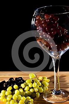 Wine grapes in glass. Green red and black grape varieties