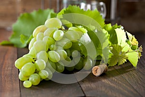 Wine grapes on wooden background with wine cork.