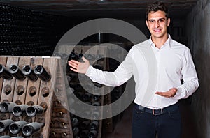 Wine maker in cellar with wine bottles storage