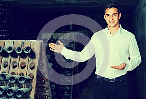 Wine maker in cellar with wine bottles storage