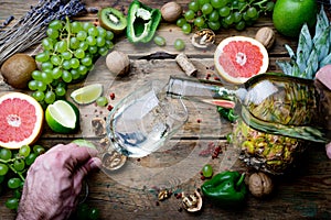 Wine maker pouring young white bio wine for tasting with grapes, nuts and fruit on the old wooden table