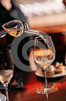 Wine is poured into a glass through an aerator at a tasting in a bar. Soft focus and natural light