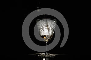 Wine pouring in beautiful misted vintage glass on black background