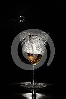 Wine pouring in beautiful misted vintage glass, black background