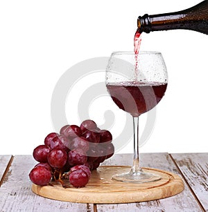 wine pouring into glass with grape and bottles