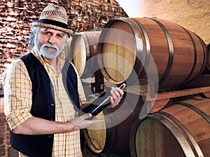 Wine producer showing his bottle of wine in front of the barriq