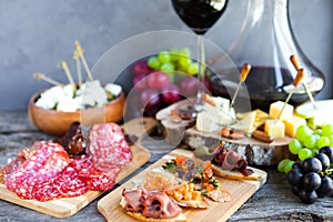 Wine snack set. Glass of red wine, grape, cheese, over rustic wooden background.