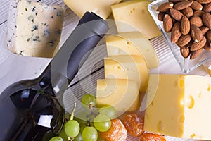 Wine with snacks - various types of cheese, figs, nuts, honey, grapes on a wooden boards background