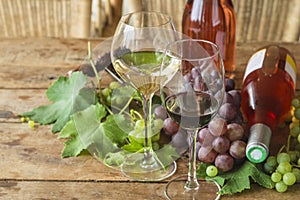 Wine tasting concept. Two glasses of red an white wine, grapes and two bottles of pink