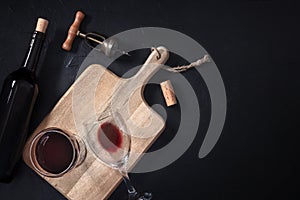 Wine tasting. A cork, a vintage corkscrew, a bottle, and two glasses, shot from above on a black background