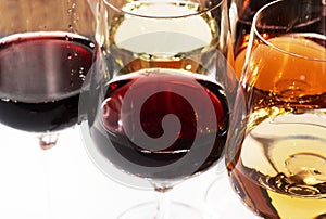 Wine tasting. Red wine shaking in glass on background with selection of red, white and rose wines in glasses and bottles