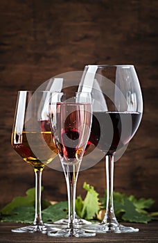 Wine tasting. Red, white, rose and champagne - still and sparkling wines sin glasses on vintage wooden table background photo