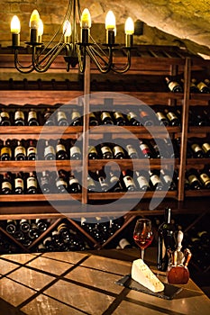 Wine vault. Nice composition of wine glass, cheese and accessories on a wooden table.