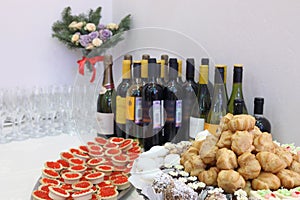 Wine, wineglasses, cakes and tartlets with red photo