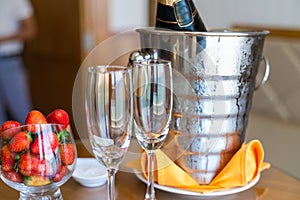 Wineglass and a bottle of chilled champagne are in an ice bucket for welcoming guests in hotel