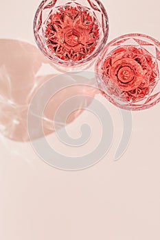 Wineglass close up, two glasses of rose wine in bright sunlight. Summer alcohol drinks concept. Pink monochrome photo