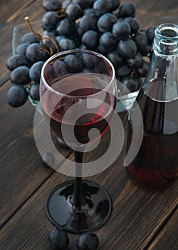 A wineglass of fresh young red wine with glass bottles and a bun