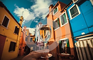Wineglass in hand of traveler in Venice. Water canals and embankments with bar and restaurants of famous italian city