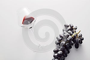 Wineglass with red wine, bunch of dark-colored grape.