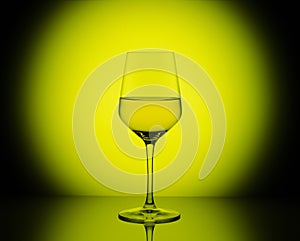 Wineglass with white wine on yellow round background