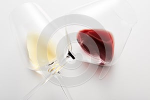 Wineglasses with red, white wine lying with stems crossed.