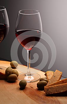 Wineglasses with red wine on wood with cheese and green olives. studio background