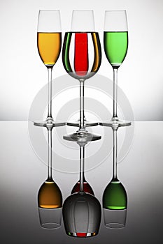 Wineglasses on a shiny surface with different colour fluids that