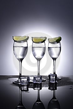 Wineglasses with vodka on a white and gray background with lime