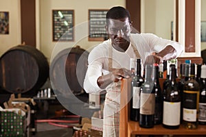 Winemaker arranging bottles in wine shop