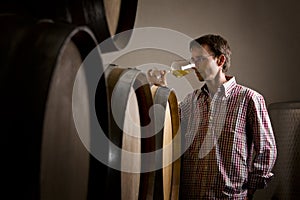 Winemaker in cellar smelling white wine in glass.