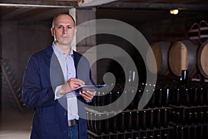 Winemaker with clipboard in wine cellar