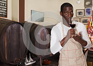 Winemaker inviting to wine shop, offering glass of wine