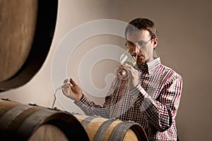 Winemaker tasting wine in cellar.