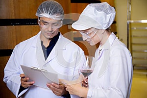 Winemaker team checking and examining producing wine at winery in factory, inspector checking quality and fermenting wine storage.