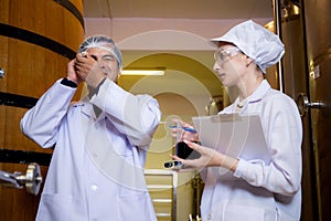 Winemaker team checking and examining producing wine at winery in factory, inspector checking quality and fermenting wine storage.