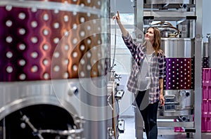 Winery worker woman walk and check the process of the machine in the modern factory with happiness