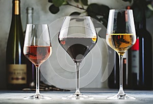 Wines assortment. Red, white, rose wine in wineglasses and bottles on gray background. Wine bar, shop, tasting concept