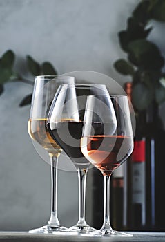 Wines assortment. Red, white, rose wine in wineglasses and bottles on gray background. Wine bar, shop, tasting concept