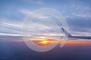 Wing of the air plane on the sea of cloud sunset sky background from window airplane