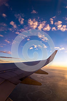 Wing of the air plane on the sea of clouds sunset sky background