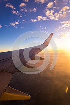 Wing of the air plane on the sea of clouds sunset sky background