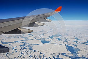 The wing of the aircraft over the Arctic ocean