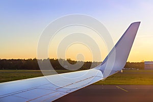 Wing of aircraft over the runway at sunset. Riga