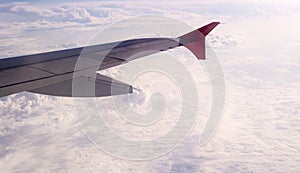 Wing of aircraft with the snow-white clounds on background