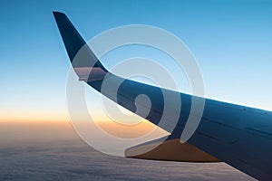 Wing of airplane above clouds at sunset