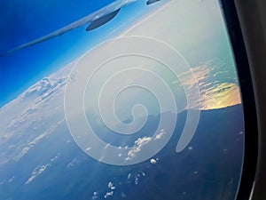 The wing of an airplane against clear blue sky and white clouds above the sea. Horizontal photo, travel concept