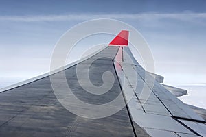 Wing of airplane from Air in the sky winglet red colored airline blue sky clouds